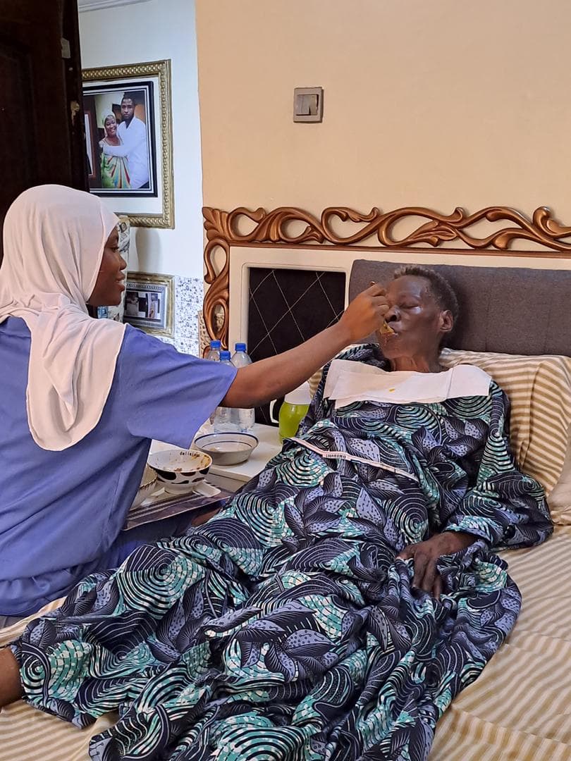 A care team member attending to an older woman at her bedside