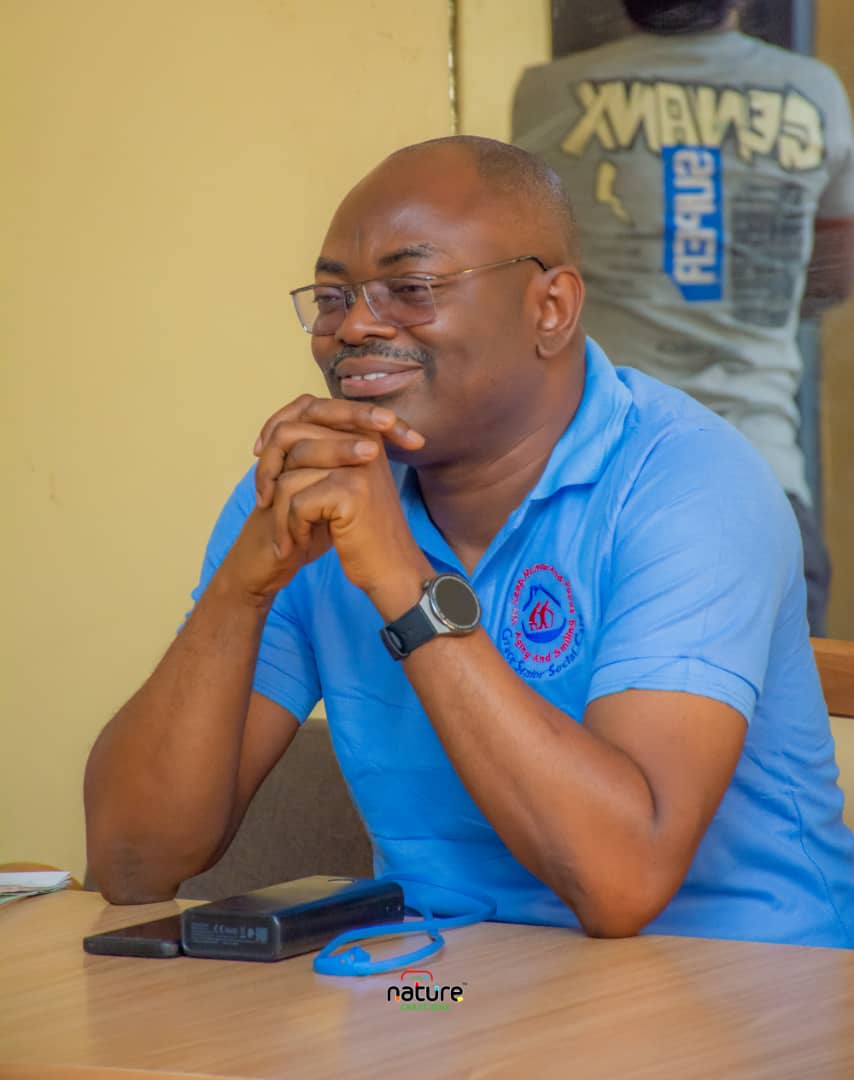Dr. Oludotun Bankole seated at a table wearing a blue Grace Senior Social Care polo shirt